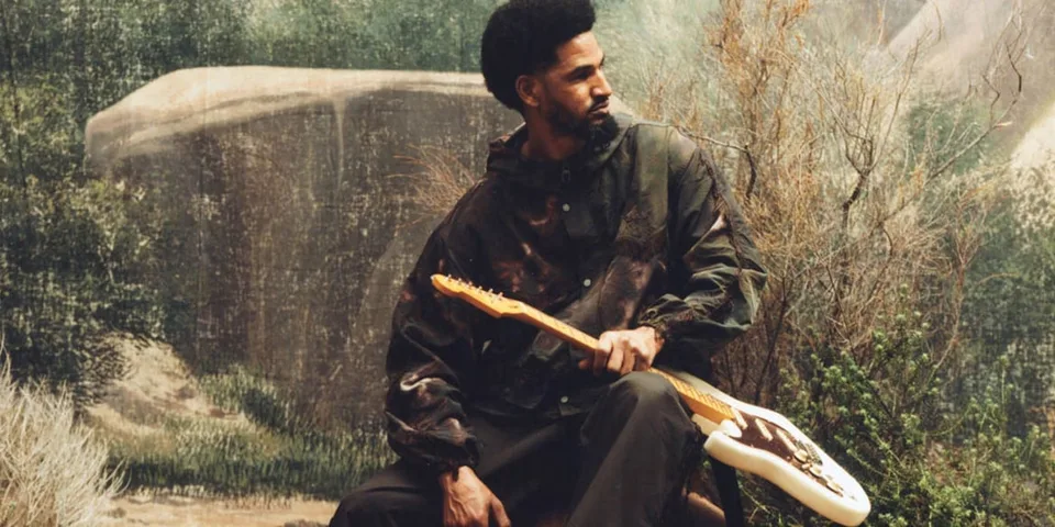 Homme assis avec guitare et fond naturel artistique.