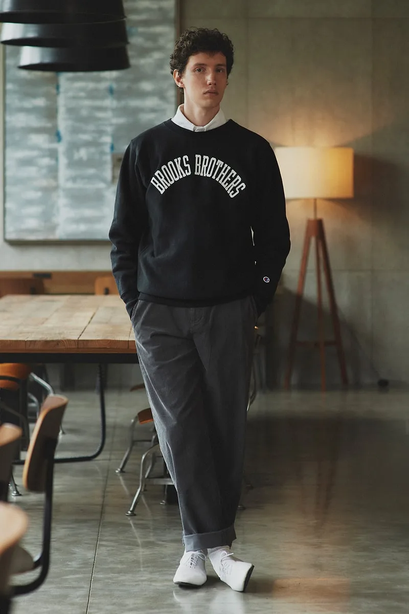 Homme en pull noir Brooks Brothers dans une pièce moderne.