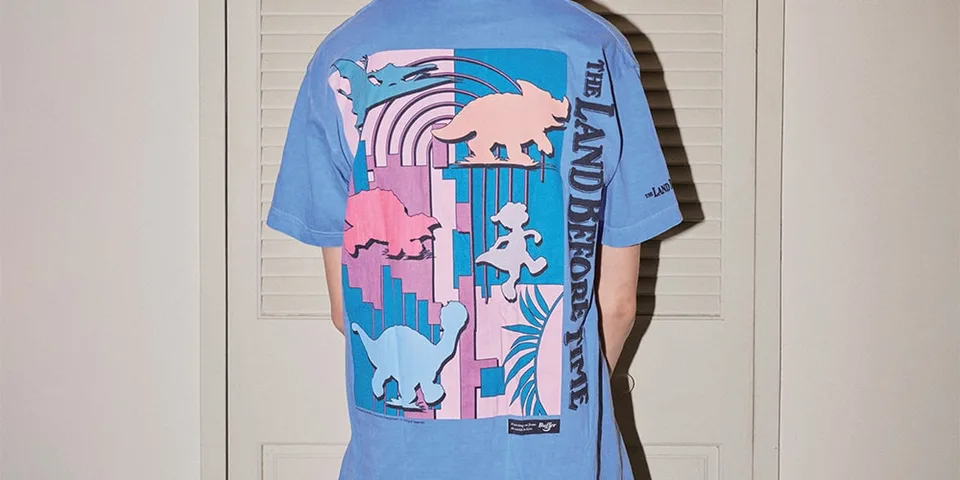 Dos d'un t-shirt bleu avec motifs de dinosaures et texte.
