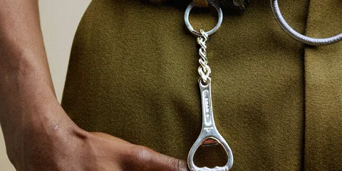 Gros plan d’un porte-clés décapsuleur argenté sur un vêtement kaki