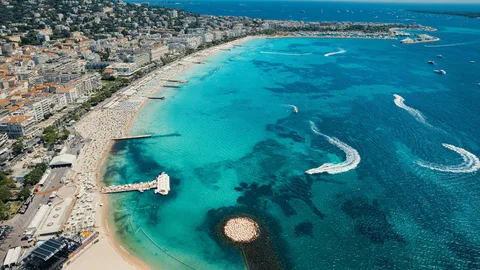Vue aérienne d'une plage fréquentée avec mer turquoise et bateaux à moteur