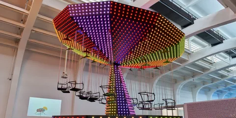 Manège lumineux avec chaises volantes dans un bâtiment moderne.