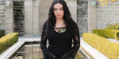Femme en robe noire devant un jardin avec fontaine.