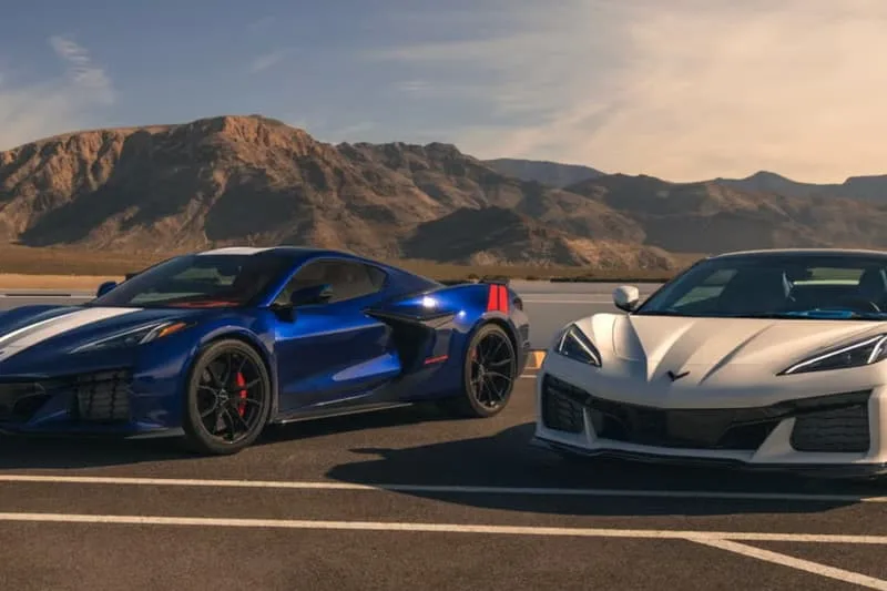 Deux voitures de sport garées devant un paysage montagneux.