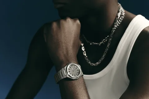 Homme avec montre en métal et colliers, fond bleu