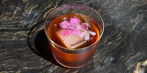 Cocktail avec fleur rose sur fond de marbre sombre.