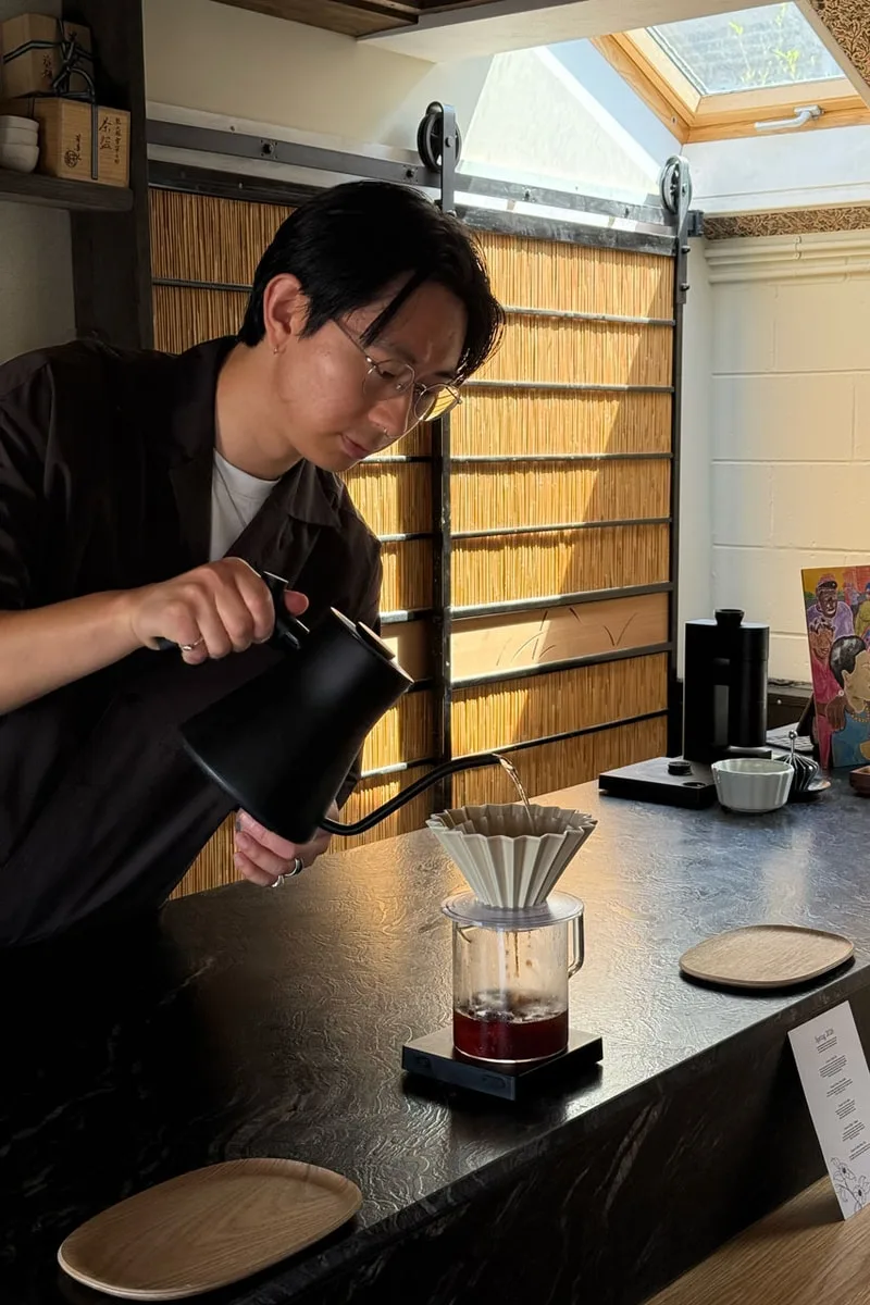 Personne préparant du café filtre avec une théière noire.