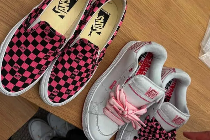 Deux paires de chaussures Vans sur une table en bois.