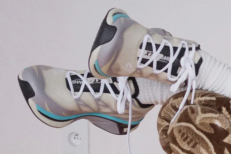 Chaussures blanches et grises avec détails bleus et lacets blancs sur fond neutre.