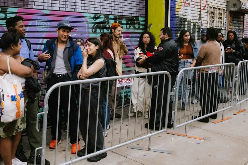 File de personnes attendant devant un mur graffité en ville.