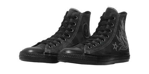 Chaussures noires montantes avec coutures blanches et étoiles.