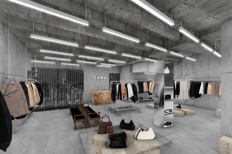 Intérieur de magasin moderne avec vêtements suspendus et sacs à main sur le sol.