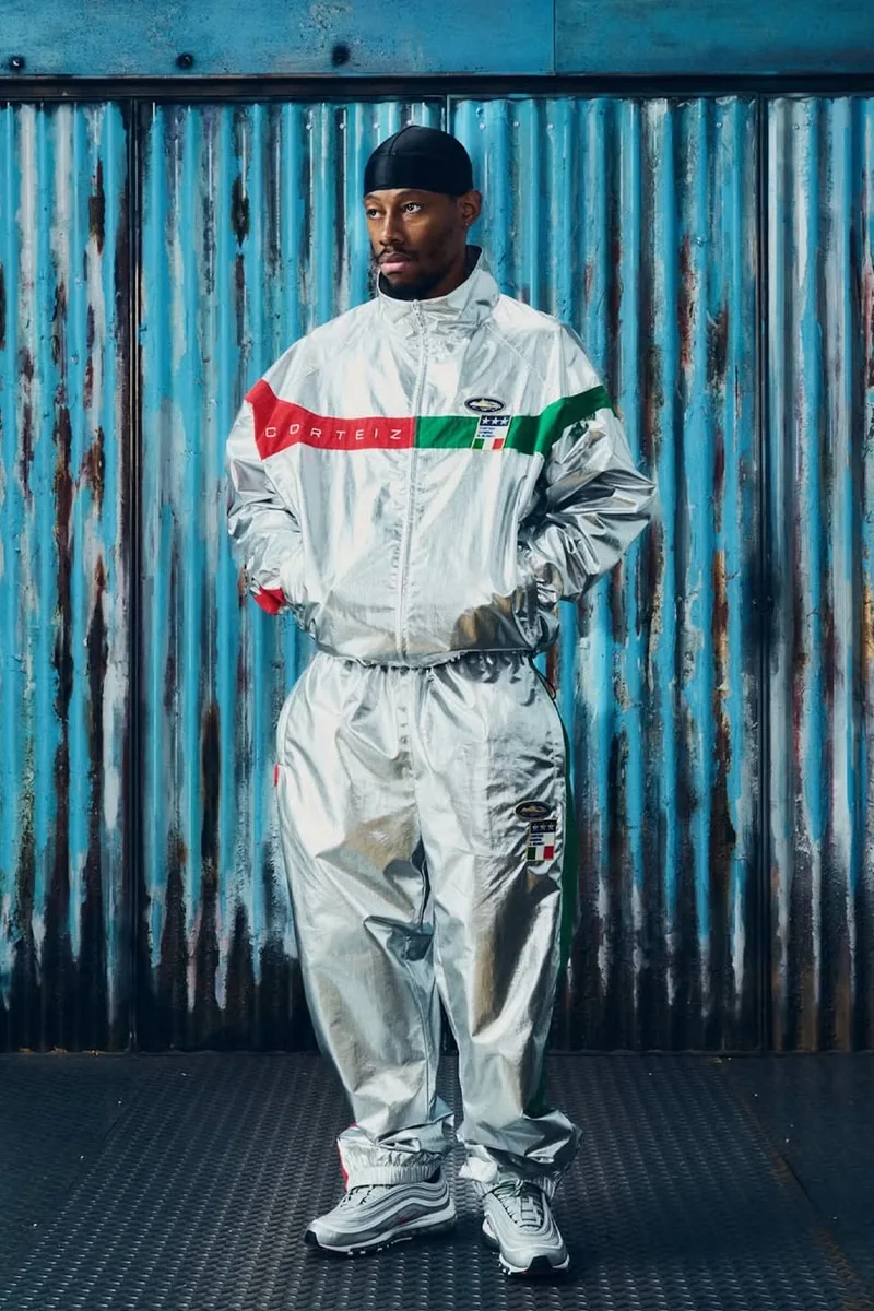 Personne en tenue argentée devant mur métallique.