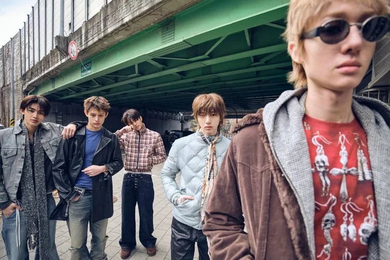 Cinq hommes posant sous un pont avec des tenues modernes.