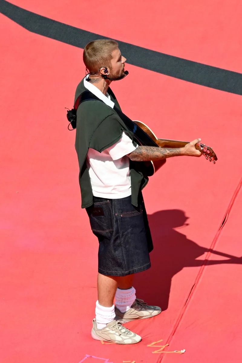 Personne jouant de la guitare sur scène rouge, look décontracté.