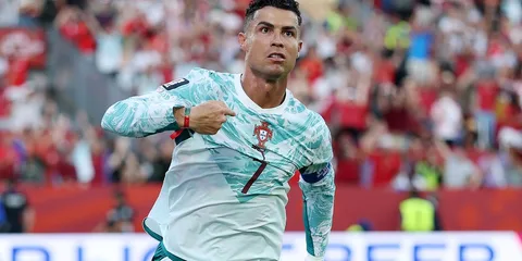 Joueur de football en tenue blanche avec public en arrière-plan.
