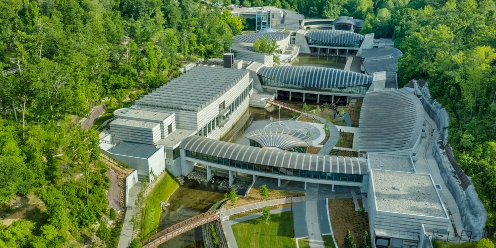 Vue aérienne d'un musée moderne entouré de verdure et d'eau.