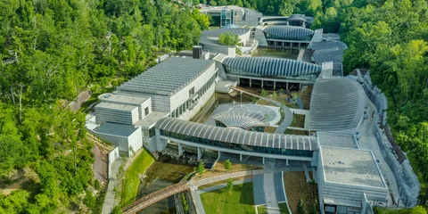 Vue aérienne d'un musée moderne entouré de verdure et d'eau.