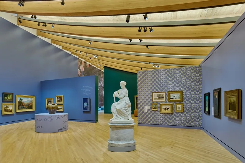 Intérieur de musée avec peintures et statue blanche.