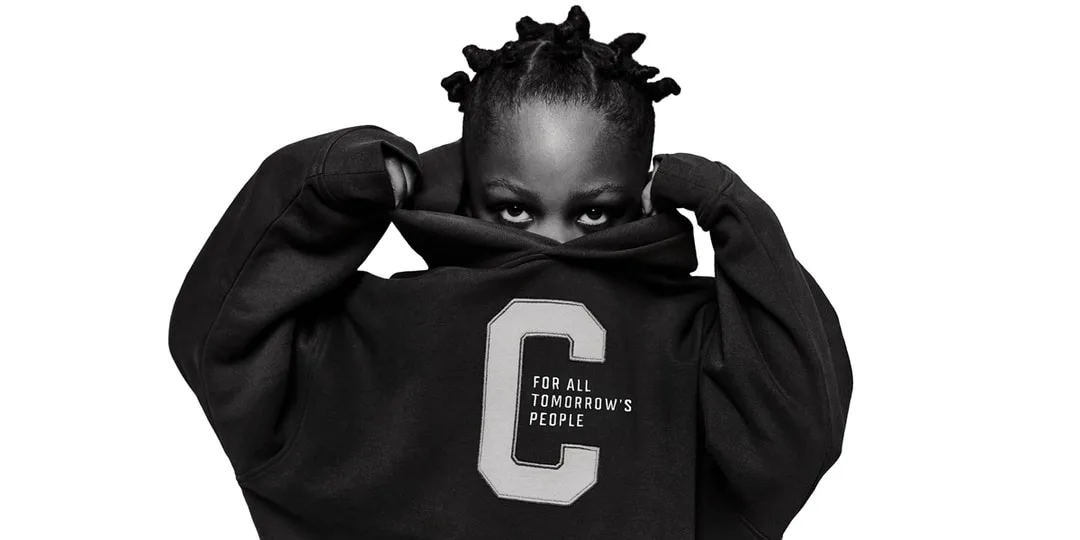 Personne en sweat-shirt noir avec lettre C, se cachant le visage.