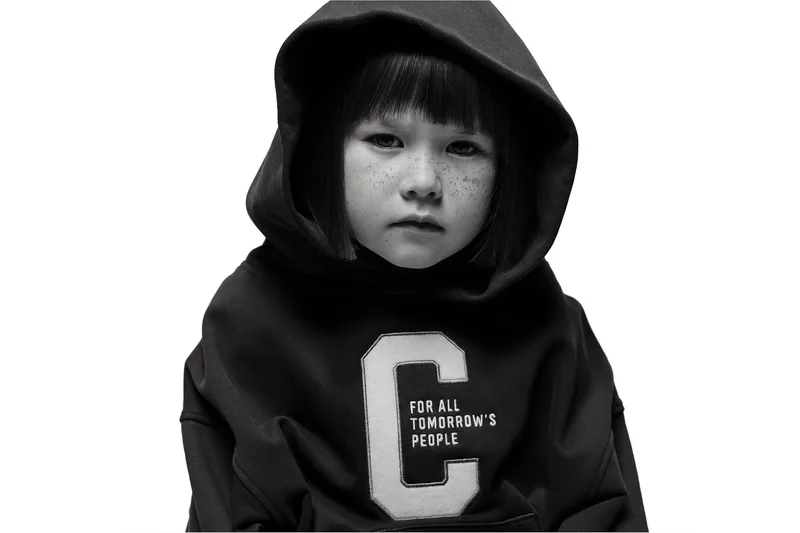 Enfant avec un sweat à capuche sombre et des taches de rousseur.
