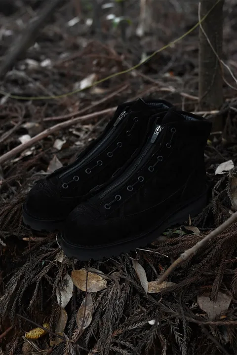 Chaussures noires sur un sol forestier avec des feuilles sèches.