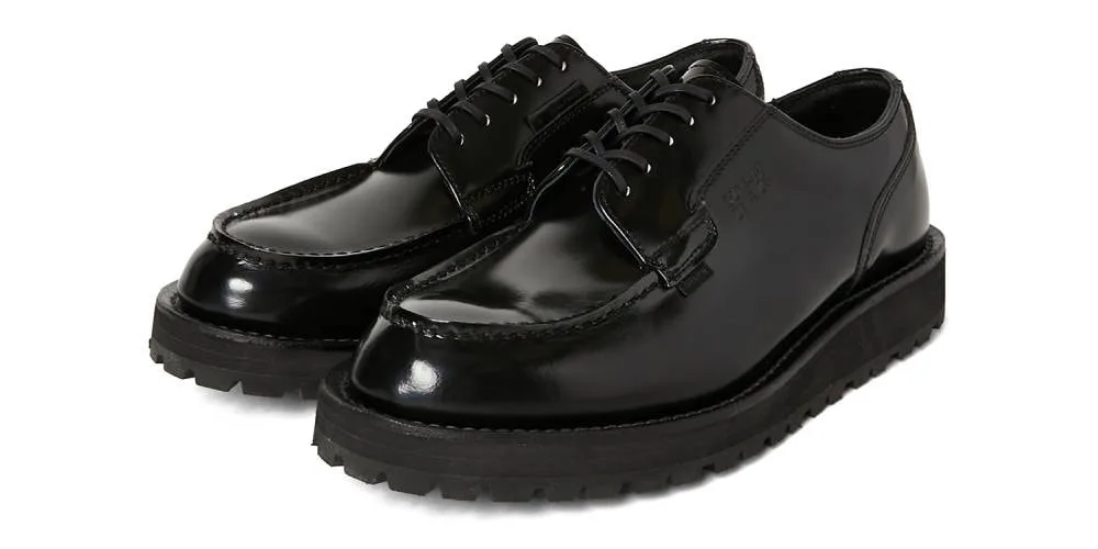 Chaussures noires brillantes avec semelle épaisse et lacets.