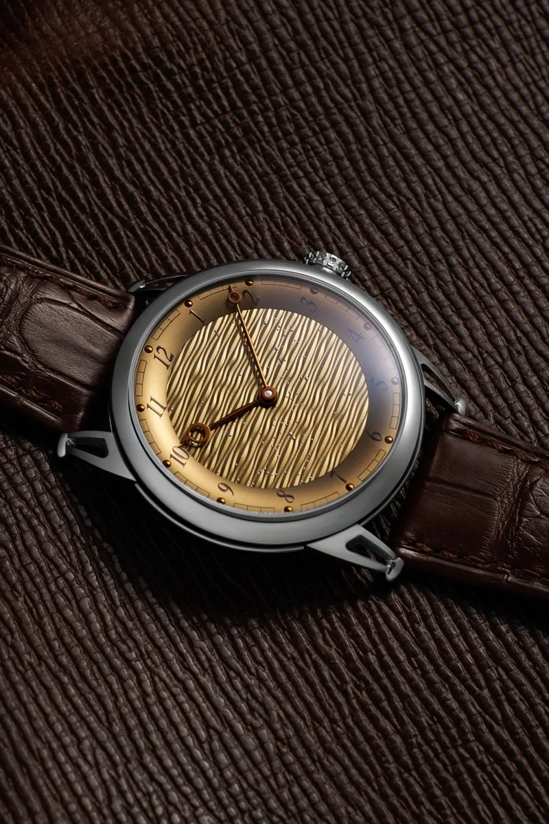 Montre avec cadran texturé doré et bracelet en cuir marron.