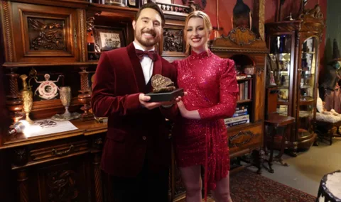 Deux personnes souriantes dans une pièce élégante avec trophée.