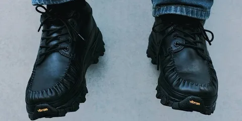 Chaussures noires en cuir avec semelles Vibram, portées avec un jean.