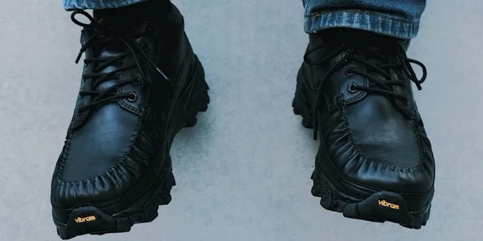 Chaussures noires en cuir avec semelles Vibram, portées avec un jean.