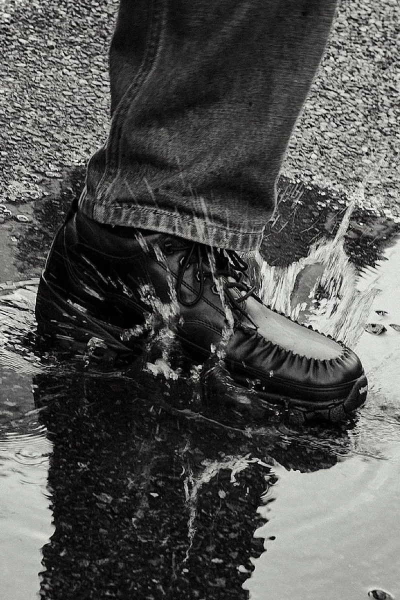 Une chaussure éclabousse de l'eau en marchant dans une flaque.