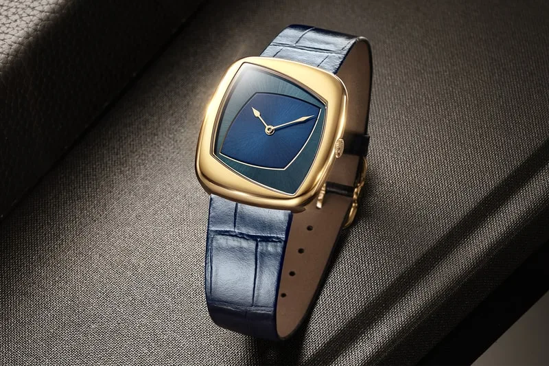 Montre élégante avec cadran bleu et bracelet en cuir bleu sur surface texturée.