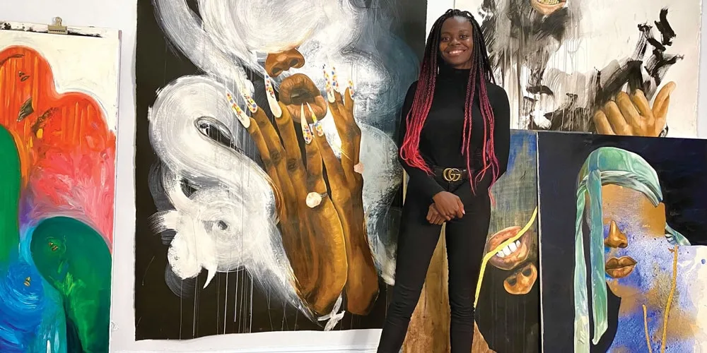 Femme debout devant des peintures colorées dans un atelier.