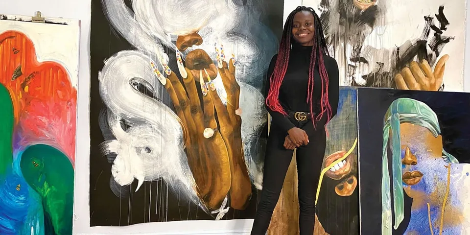 Femme debout devant des peintures colorées dans un atelier.