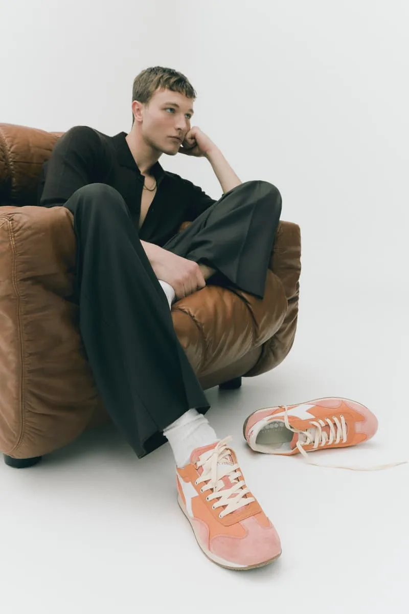 Homme assis dans un fauteuil avec des baskets orange à côté