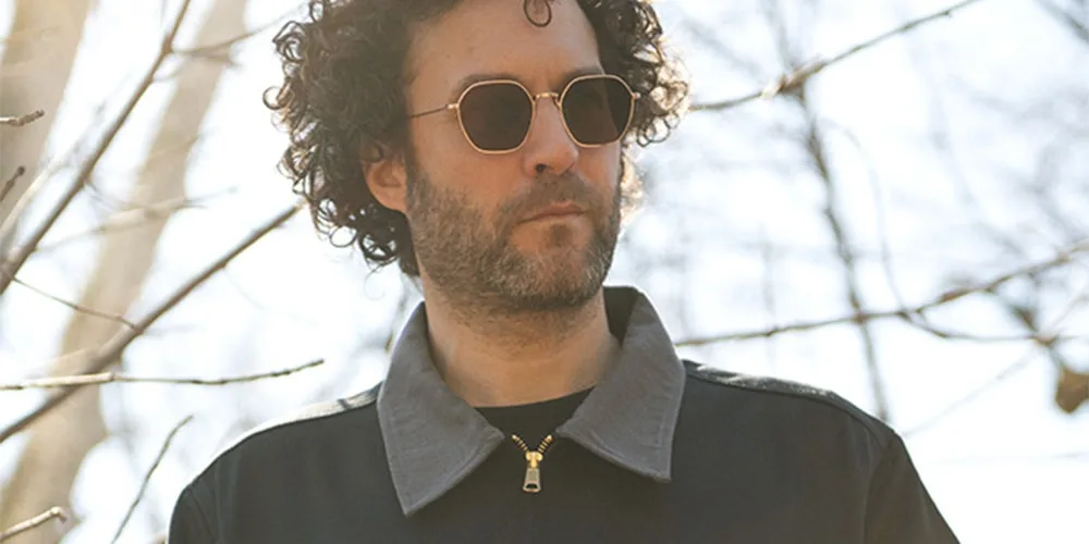 Homme portant des lunettes de soleil et veste sombre, jour ensoleillé