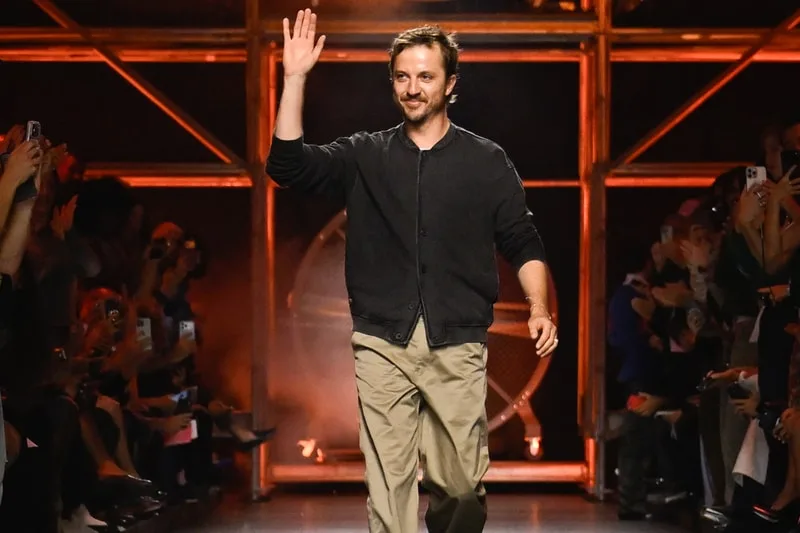 Homme saluant sur une passerelle de mode, public applaudissant