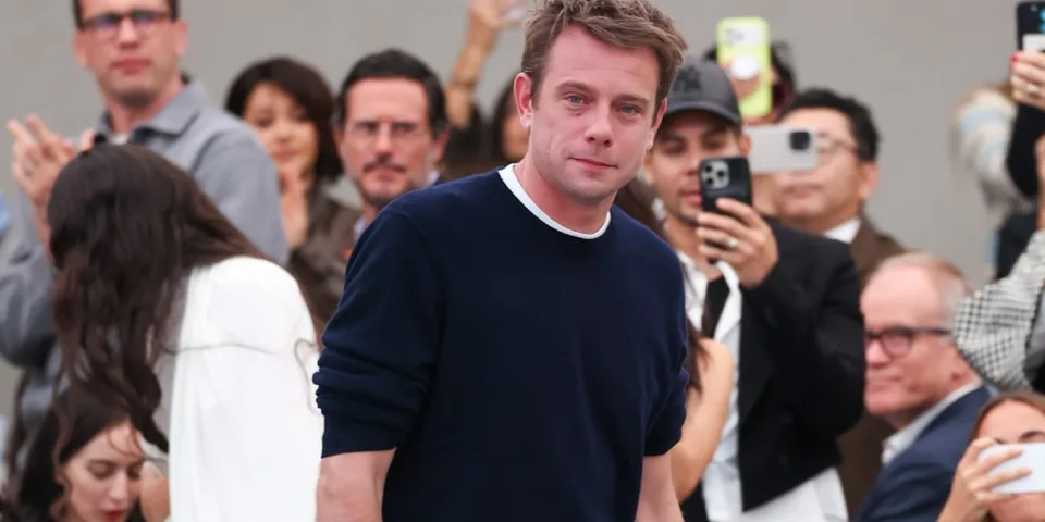 Un homme en pull bleu dans une foule avec des smartphones.