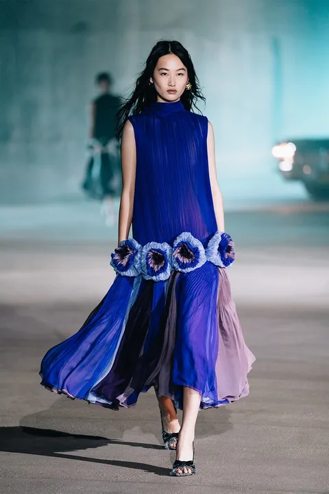 Femme en robe bleue à motifs floraux sur un podium.