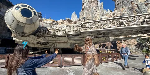 Personne déguise interagit avec visiteur devant un vaisseau spatial géant.