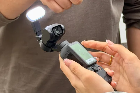Personne tenant une caméra compacte avec écran et lampe.