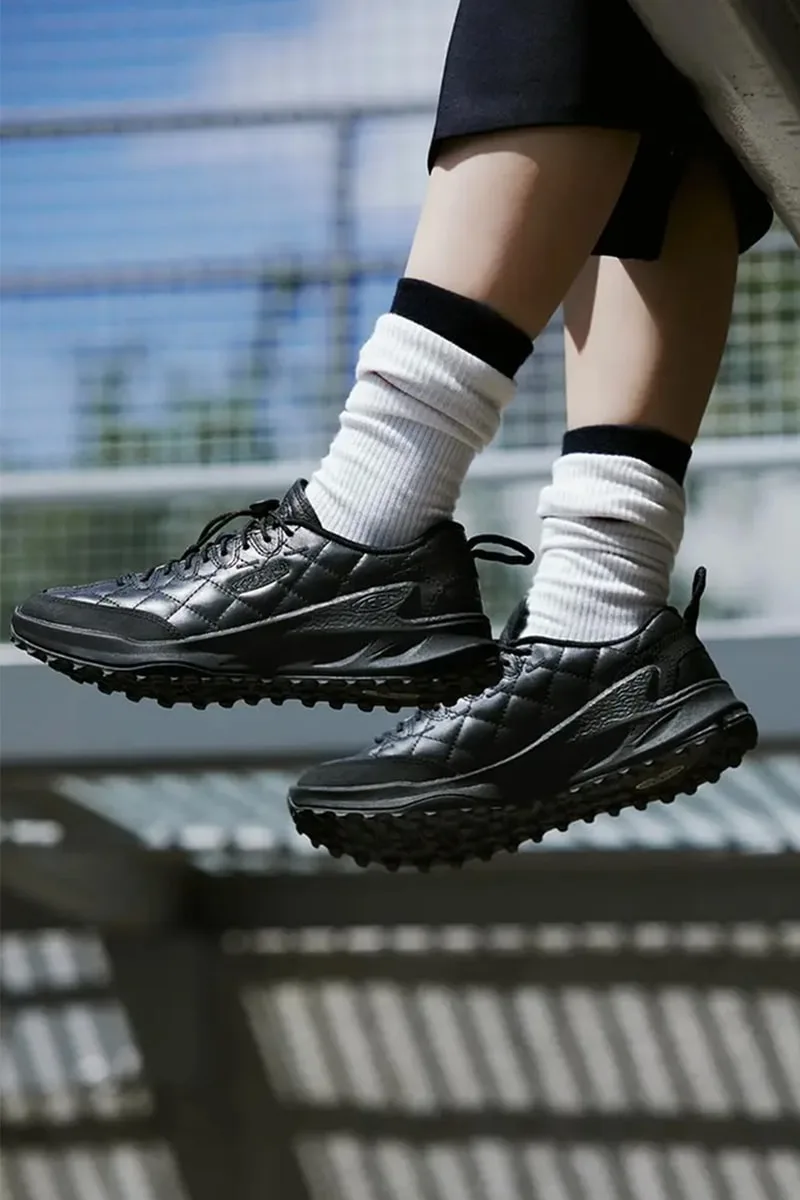 Personne portant des baskets noires et des chaussettes blanches sur un banc.