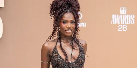 Femme avec une robe transparente marron et coiffure volumineuse.
