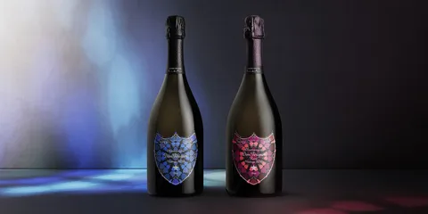 Deux bouteilles de champagne avec étiquettes colorées et fond sombre.