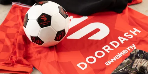 Ballon de football sur un maillot rouge DoorDash avec motif camouflage.