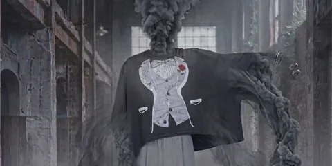 Personnage avec tête de fumée et t-shirt surdimensionné dans un bâtiment industriel.