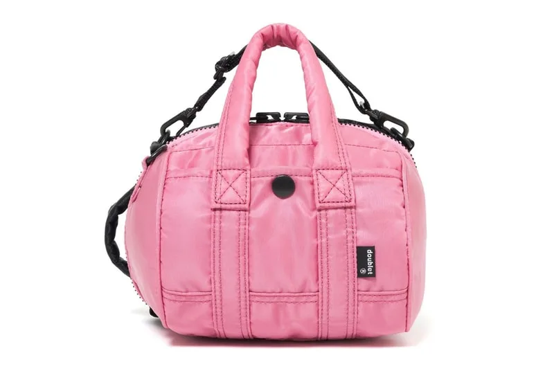 Sac rose avec bandoulière noire et détails cousus.