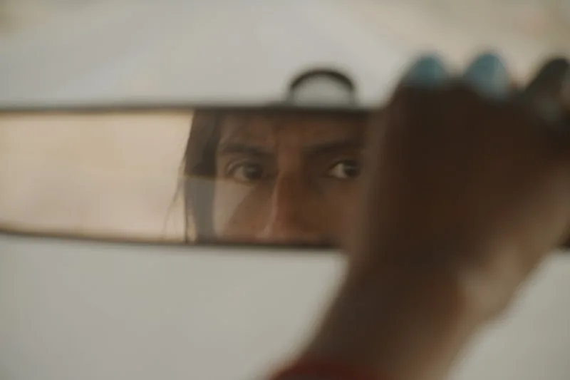 Reflet d'une personne dans le rétroviseur d'une voiture.