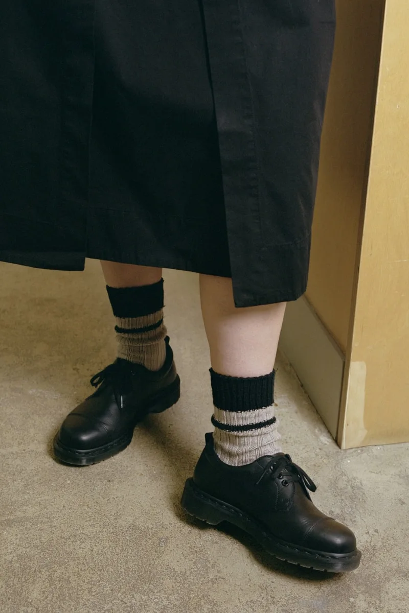 Personne portant des chaussures noires et chaussettes à rayures